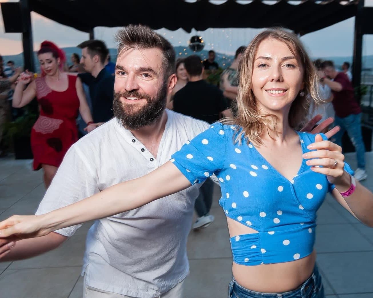 Doi dansatori zâmbind în timp ce dansează pe rooftop